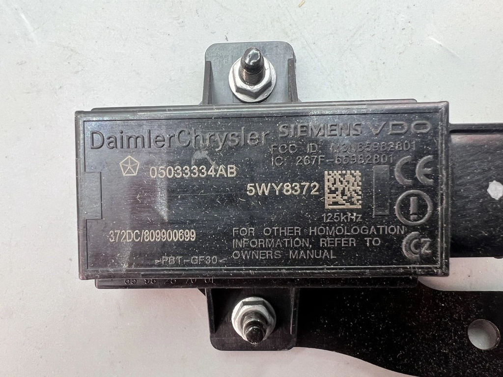 Reference image — aftermarket front TPMS trigger module 05033334AB — exact reference marking and mounting hardware close-up; external native reference only, not actual stock